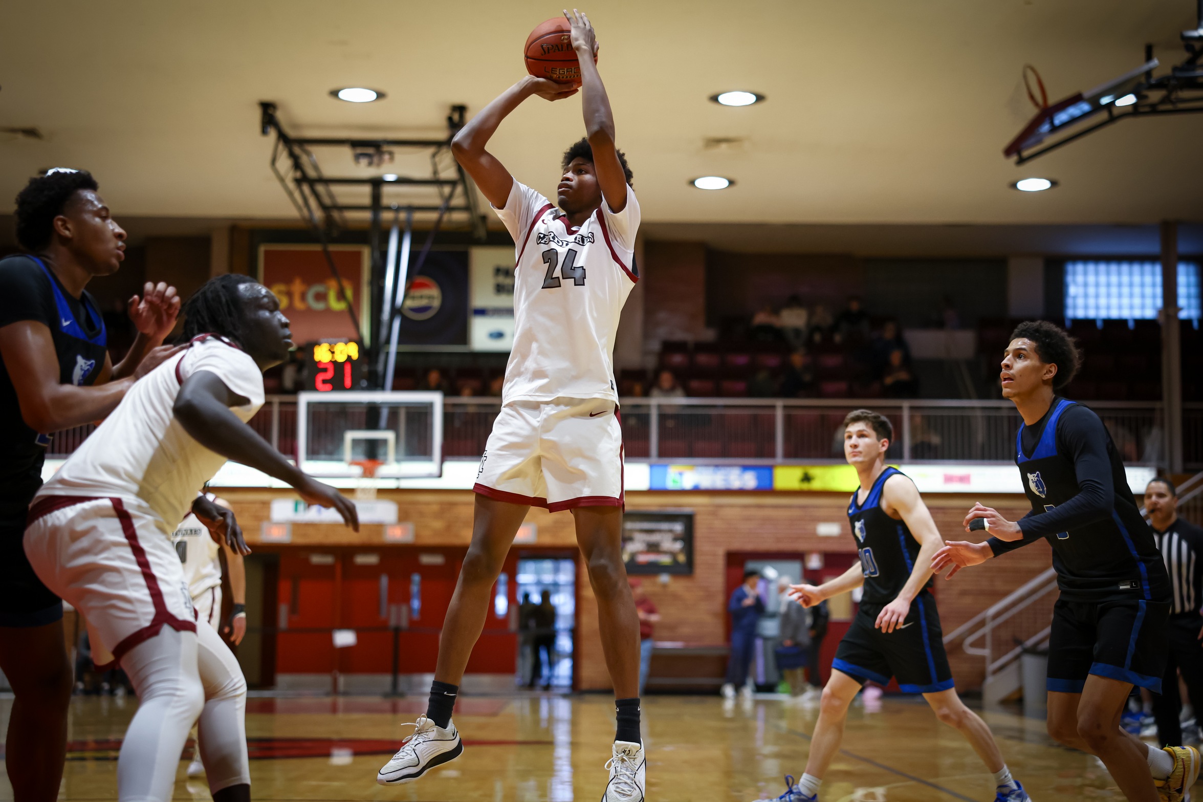 Ajayi Simmons shoots ball over defenders in Christianson Gymnasium.