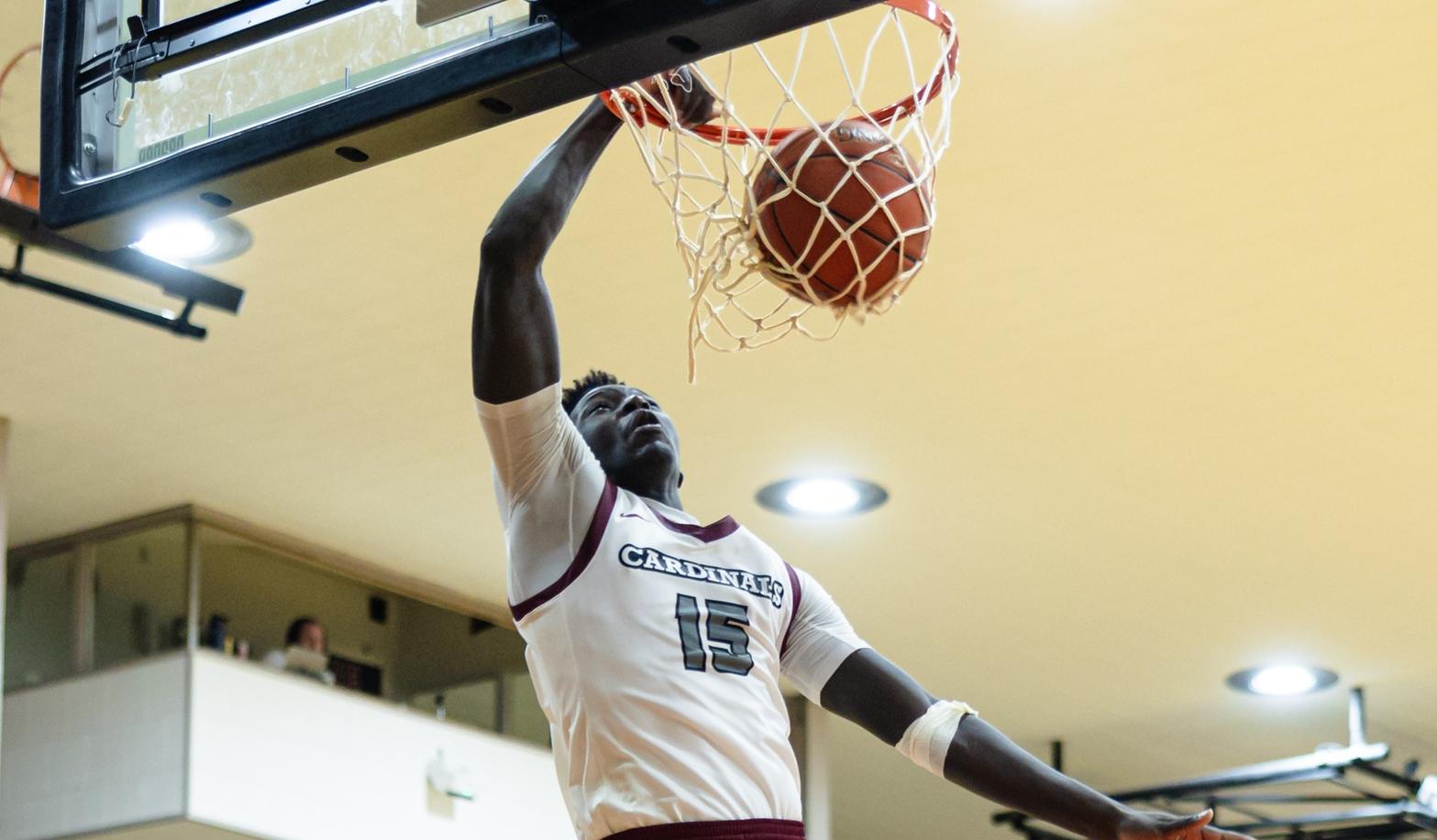 Austin Ouko dunks basketball in Christianson Gymnasium.