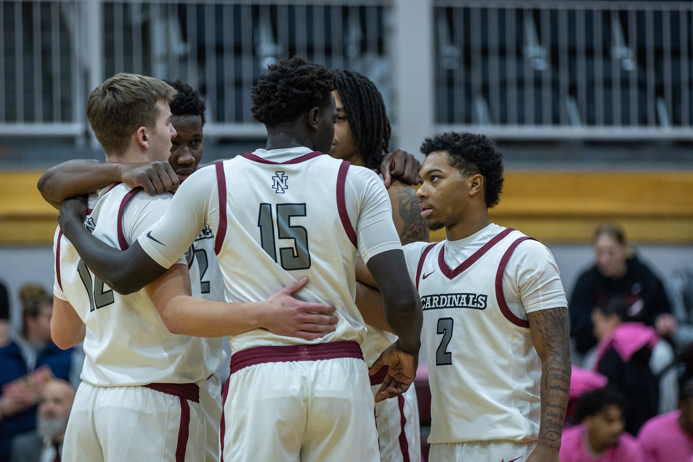 NIC men's basketball team gathers midcourth in Christianson Gymnasium during cancer awareness game.